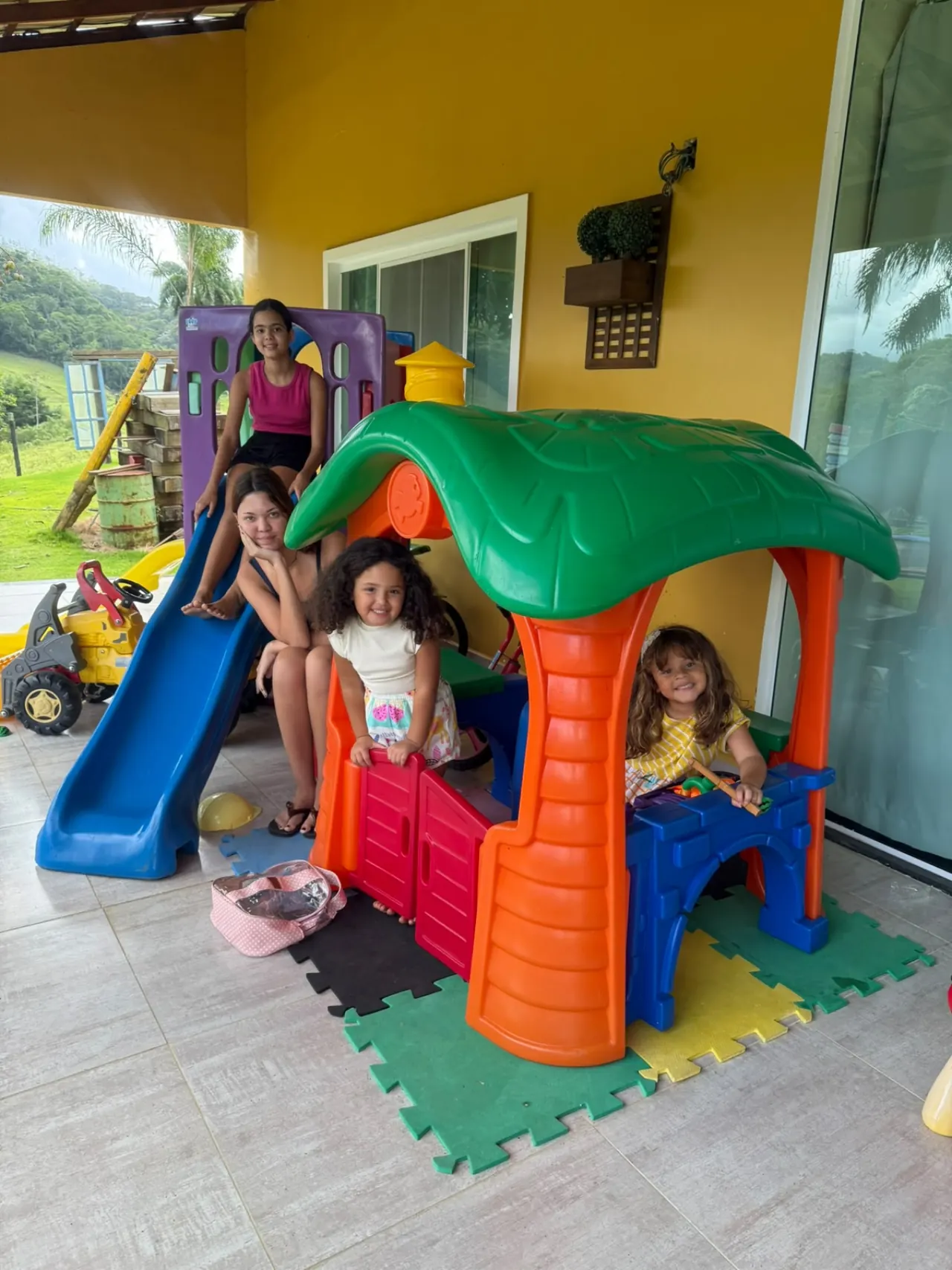 Crianças brincando na casinha colorida da área kids