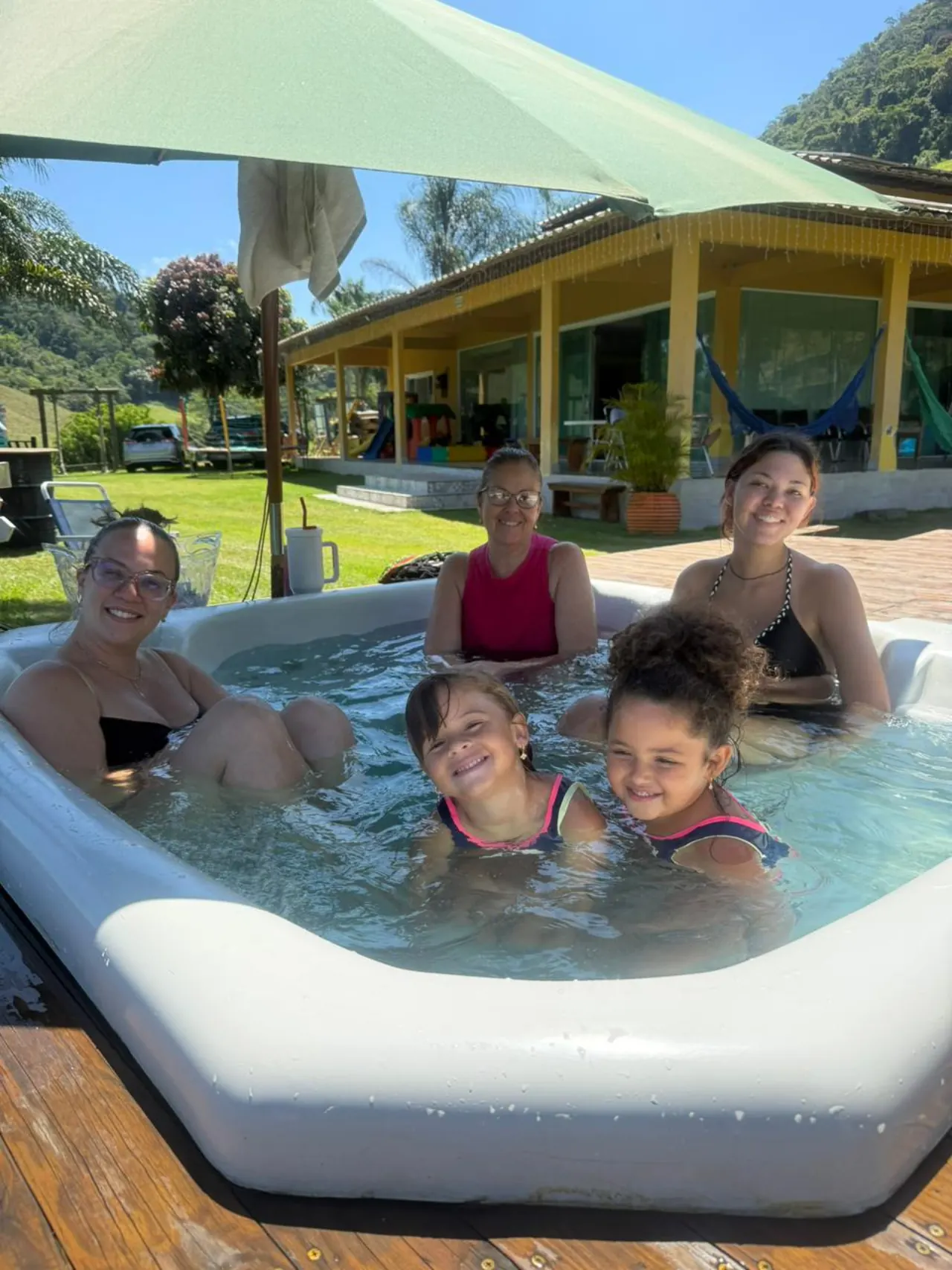Mães e crianças na piscina com vista para a casa